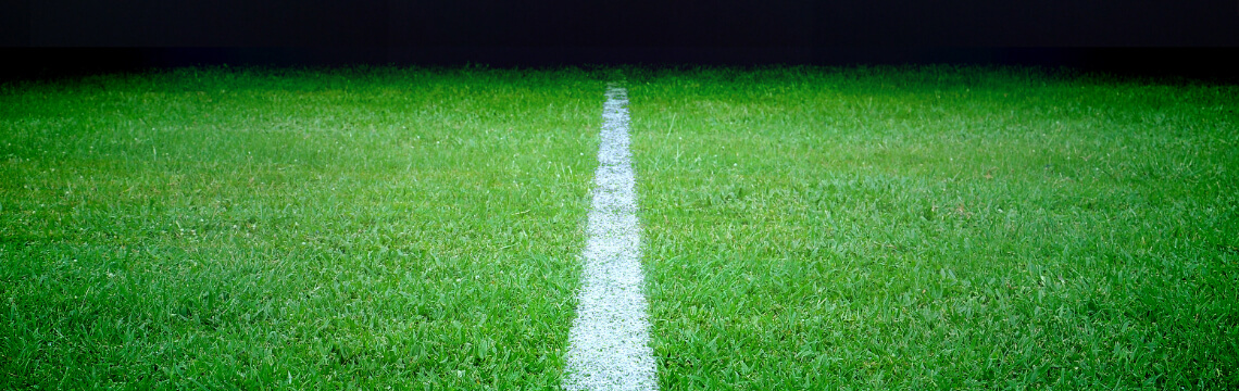 Close up view of soccer field with stadium lights in the background.