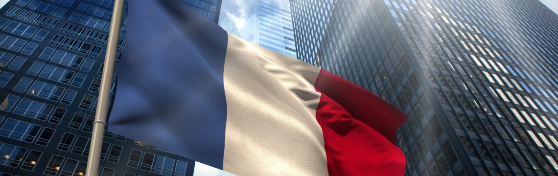 French flag waving in front of office buildings