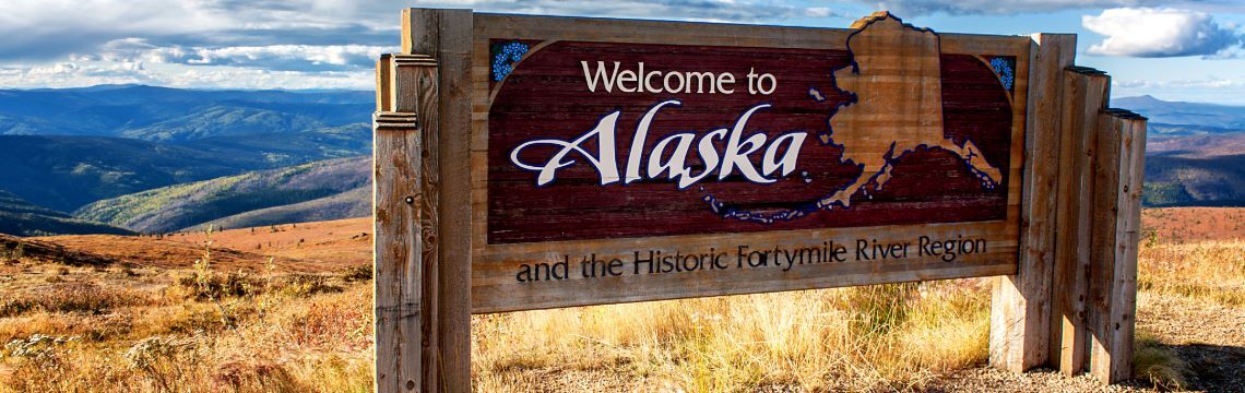 Welcome to Alaska sign with mountains in background