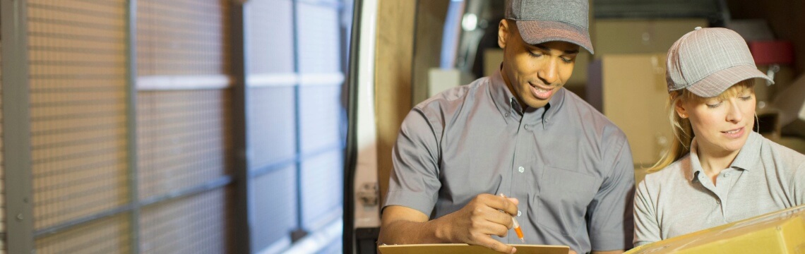Two people unloading boxes from a delivery van.