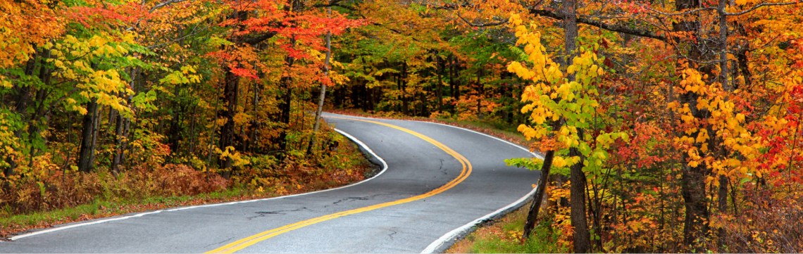 Vermont considers retail delivery fee Winding road in rural Vermont with colorful fall foliage all around it.